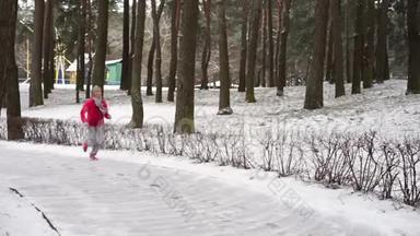 在寒冷的冬季森林里慢跑的女跑步者穿着温暖的运动服装和手套。